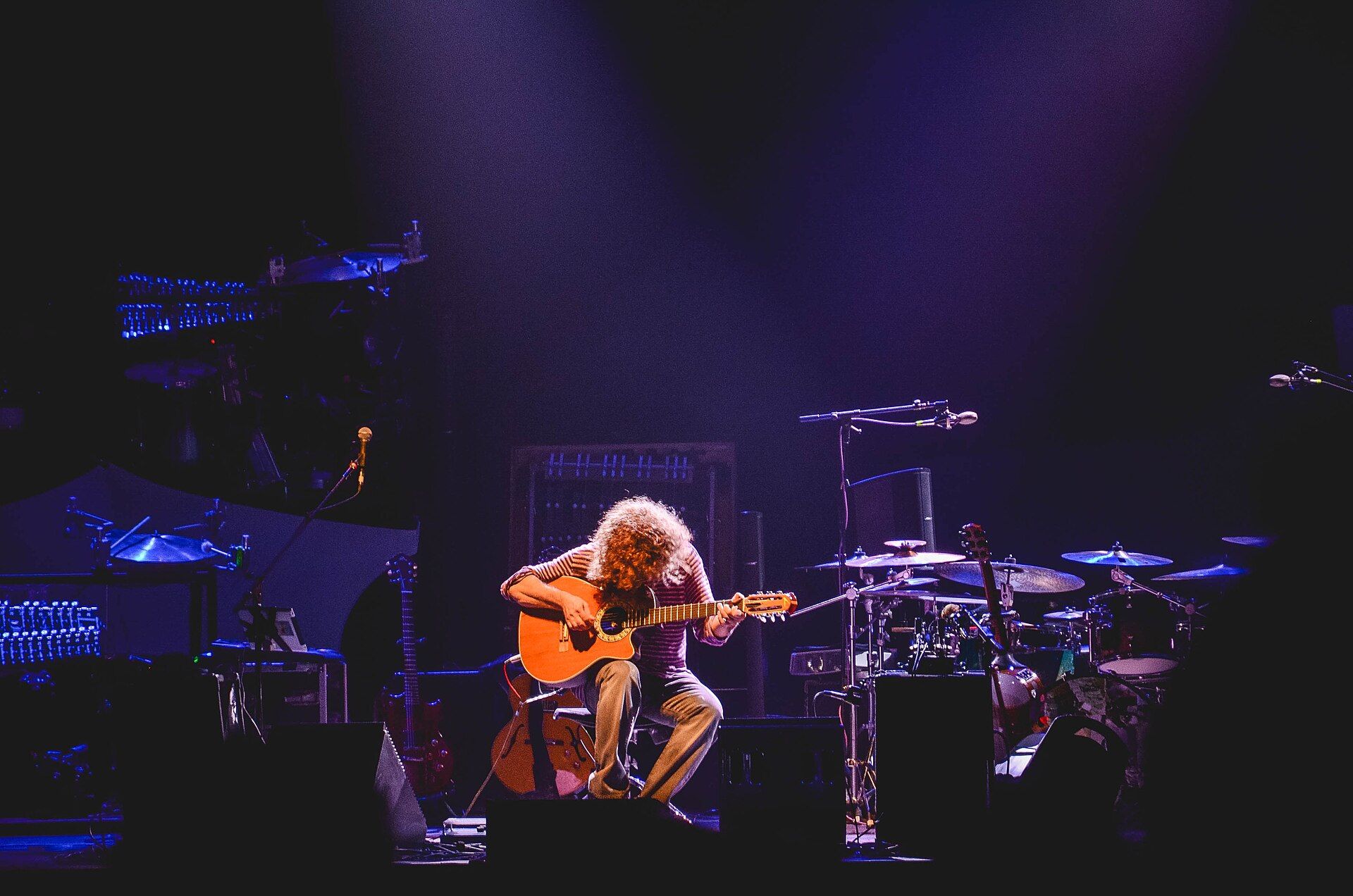 Pat Metheny seated alone with an acoustic guitar under violet stage light at L’Olympia, Paris, 2014